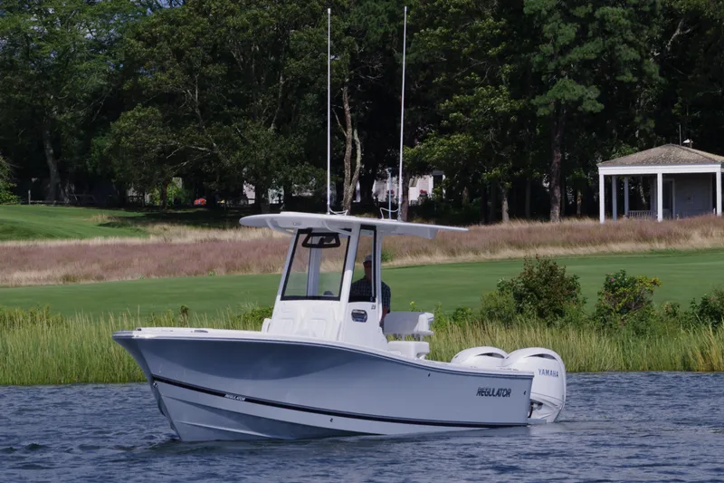 Slide: The Image of 2024 Regulator 23 boat on a serene lake with lush greenery in the background. - 7