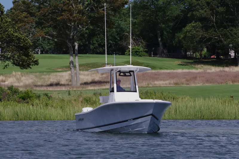 Slide: The Image of 2024 Regulator 23 boat cruising on a serene lake with lush greenery. - 9