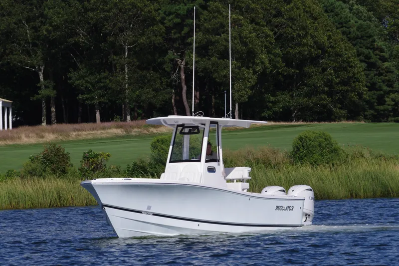 Slide: The Image of 2024 Regulator 23 boat cruising on a serene lake with lush greenery. - 0