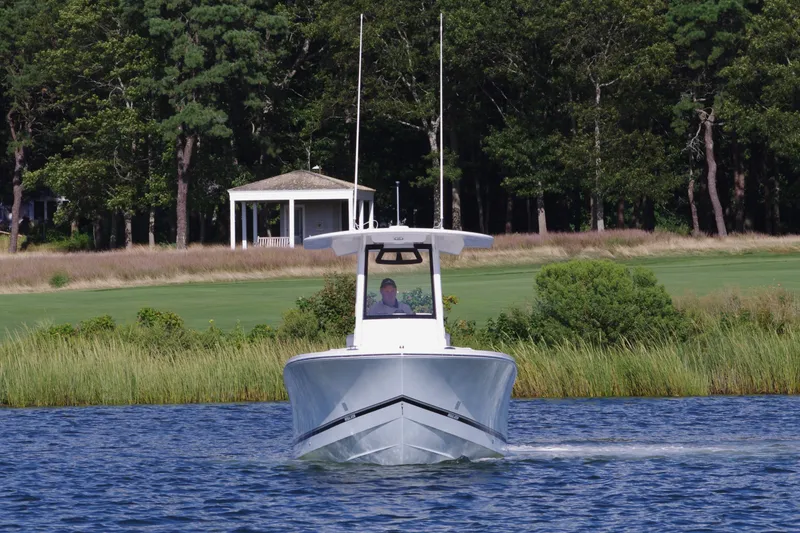 Slide: The Image of 2024 Regulator 23 boat cruising on a lake with a scenic forest backdrop. - 1