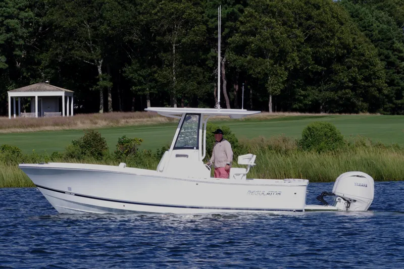 Slide: The Image of 2024 Regulator 23 boat cruising on a lake with lush greenery in the background. - 10