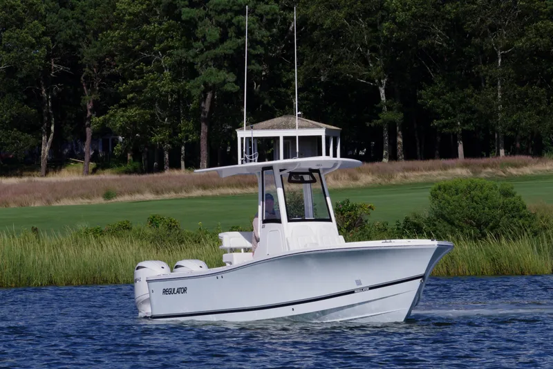 Slide: The Image of 2024 Regulator 23 boat cruising on a scenic lake with lush greenery. - 2