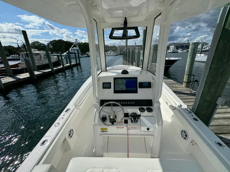 Slide: The Image of 2024 Regulator 23 boat cockpit with steering wheel and navigation system at marina. - 27