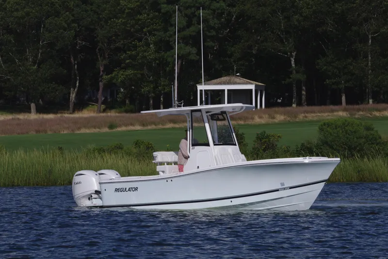Slide: The Image of 2024 Regulator 23 boat cruising on a lake with a scenic background. - 3