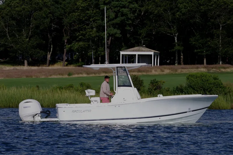 Slide: The Image of 2024 Regulator 23 boat cruising on a serene lake with lush greenery. - 4