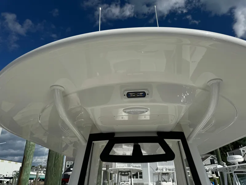 Slide: The Image of 2024 Regulator 23 boat's helm station with T-top under clear blue sky. - 49