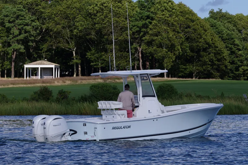 Slide: The Image of 2024 Regulator 23 boat cruising on a scenic lake with lush greenery. - 5