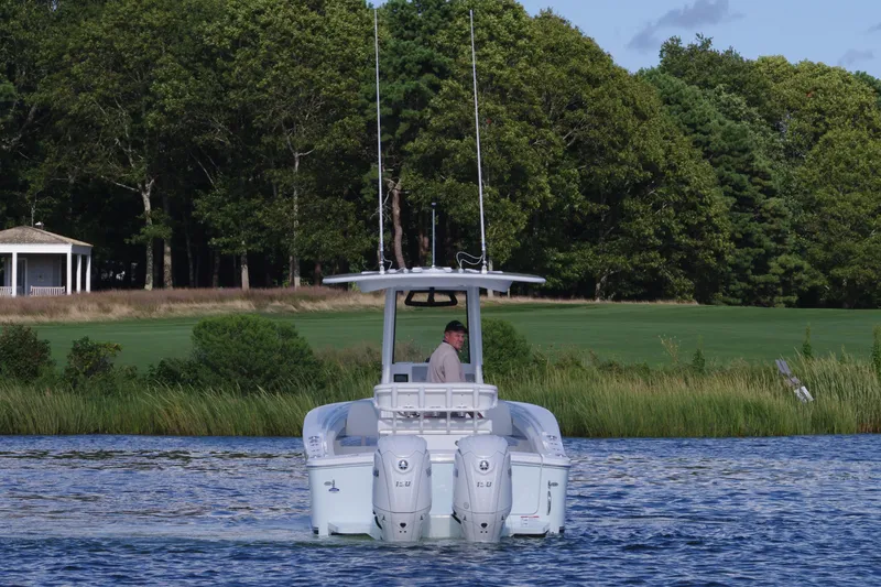 Slide: The Image of 2024 Regulator 23 boat cruising on a scenic lake with lush green trees. - 7