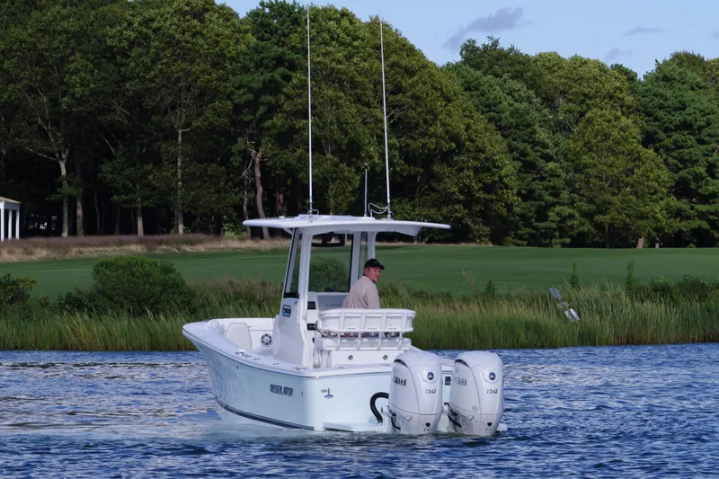 Slide: The Image of 2024 Regulator 23 boat cruising on a scenic lake with lush green trees. - 8