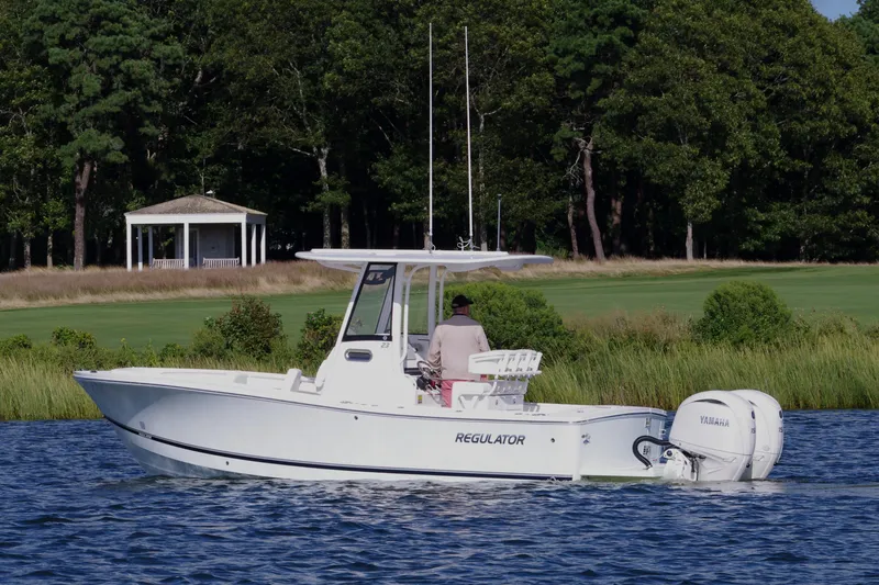 Slide: The Image of 2024 Regulator 23 boat cruising on a lake with a scenic forest backdrop. - 9