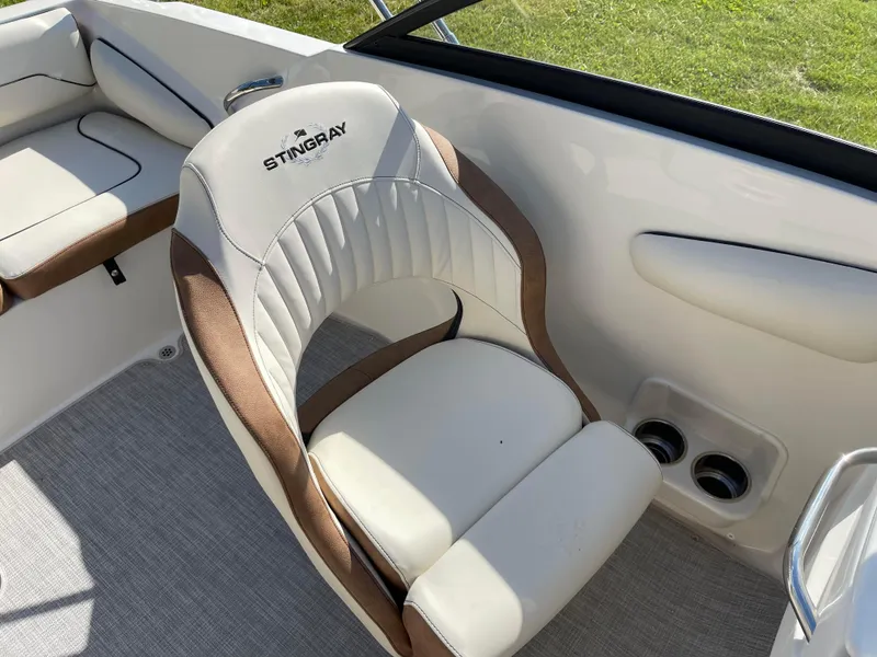 Slide: The Image of 2024 Stingray 201 DC boat interior with white and brown cushioned seating. - 14