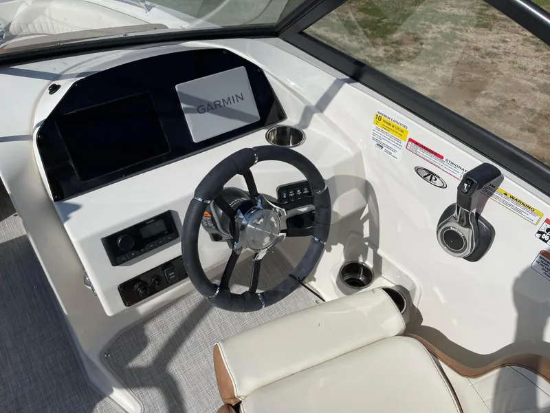 Slide: The Image of 2024 Stingray 201 DC boat cockpit with Garmin navigation system and steering wheel. - 2