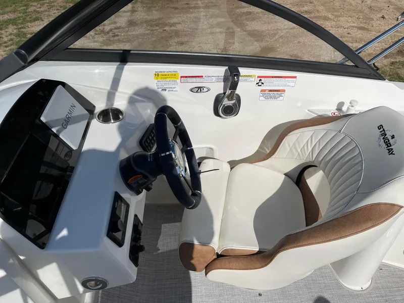 Slide: The Image of 2024 Stingray 201 DC boat cockpit with steering wheel and captain's chair. - 8