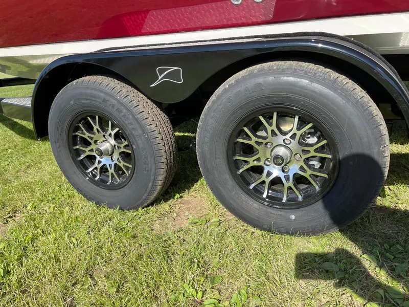 Slide: The Image of 2024 Stingray 201 DC boat trailer with dual black alloy wheels on grass. - 9