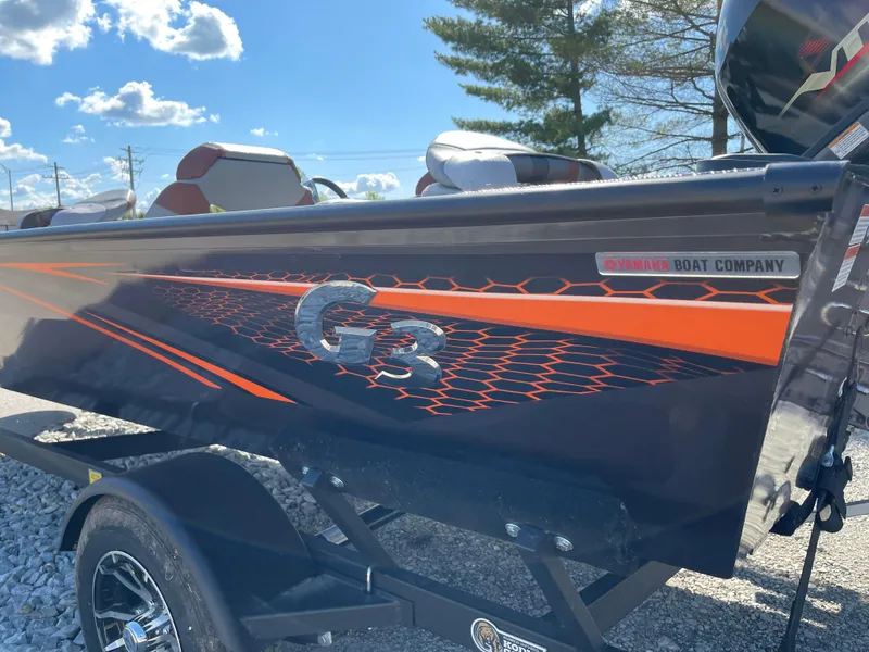 Slide: The Image of 2024 G3 Sportsman 1710 PFX boat with vibrant orange and black design on trailer. - 8
