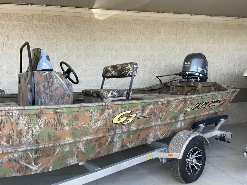 Slide: The Image of 2024 G3 Gator Tough 17 CCJ camo boat on trailer with outboard motor. - 2