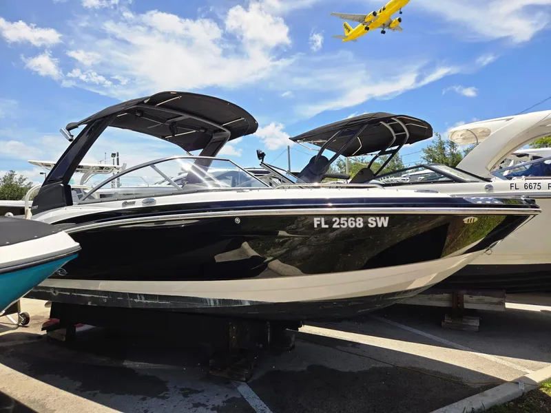 Slide: The Image of 2021 Chaparral 230 boat in black, docked with a yellow plane flying overhead. - 13