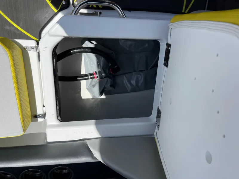 Slide: The Image of 2023 Scarab 255 Wake ID boat storage compartment with open hatch and visible hose. - 11