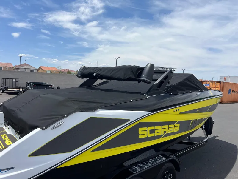 Slide: The Image of 2023 Scarab 255 Wake ID boat with black cover, parked outdoors under blue sky. - 16