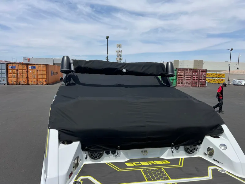 Slide: The Image of 2023 Scarab 255 Wake ID boat with black cover in an industrial area. - 17