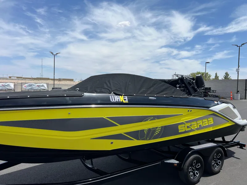 Slide: The Image of 2023 Scarab 255 Wake ID boat with vibrant yellow and black design on a trailer. - 18