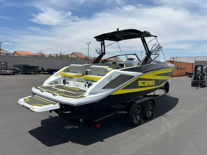 Slide: The Image of 2023 Scarab 255 Wake ID boat with vibrant yellow accents on a trailer. - 3