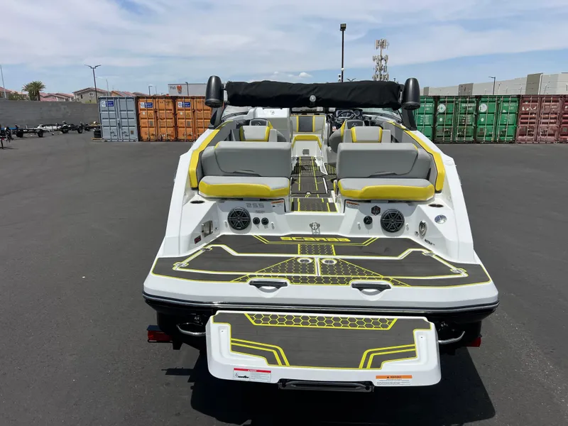 Slide: The Image of 2023 Scarab 255 Wake ID boat, rear view, in a parking lot with colorful containers. - 36