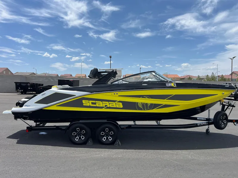 Slide: The Image of 2023 Scarab 255 Wake ID boat on trailer, black and yellow design, parked outdoors. - 37
