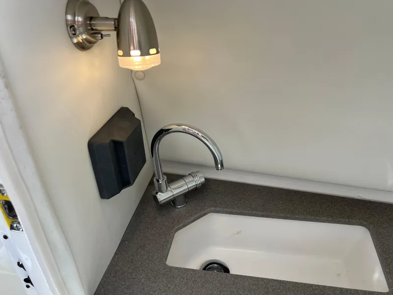 Slide: The Image of Compact sink area with modern faucet and wall light in 2023 Scarab 255 Wake ID boat. - 48