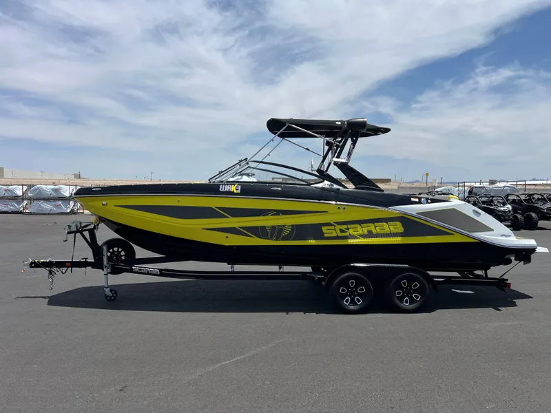 Slide: The Image of 2023 Scarab 255 Wake ID boat on trailer, sleek design, vibrant yellow and black accents. - 5