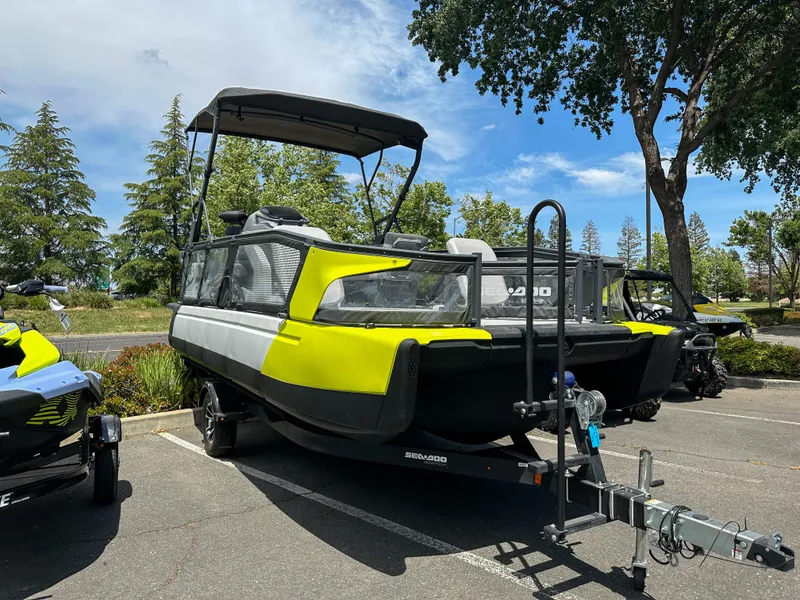 Slide: The Image of 2024 Sea-Doo Switch Sport 21 pontoon boat parked on trailer in sunny outdoor setting. - 19