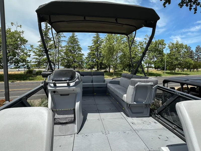 Slide: The Image of 2024 Sea-Doo Switch Sport 21 pontoon boat with canopy and seating, parked outdoors. - 7
