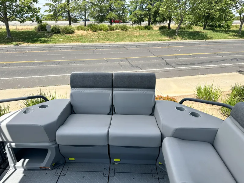 Slide: The Image of 2024 Sea-Doo Switch Sport 21 interior seating with cup holders, parked near a road. - 9