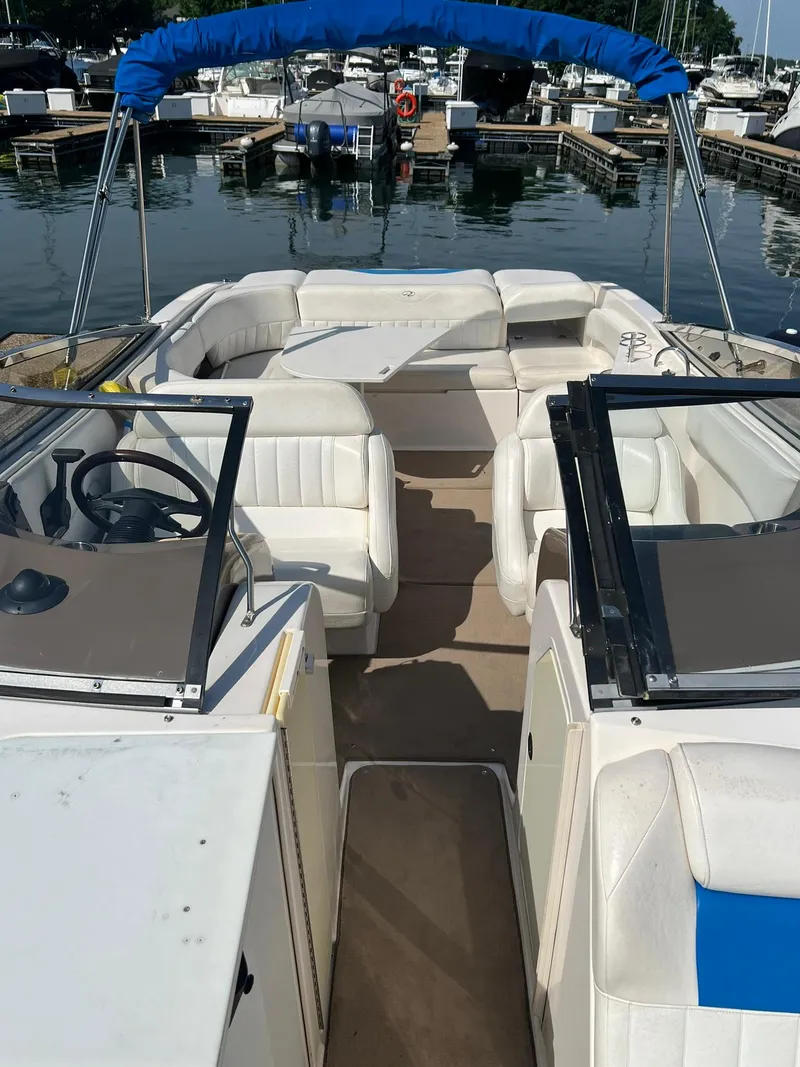 Slide: The Image of 2006 Regal 2600 Bowrider boat with white seating and blue canopy docked at marina. - 8