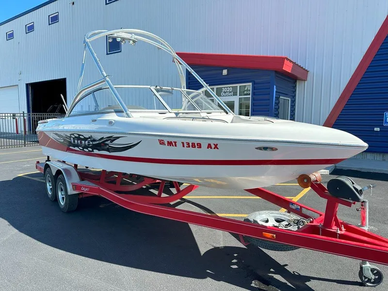 Slide: The Image of 2006 Tigé 22i boat on red trailer, parked outside a building. - 3