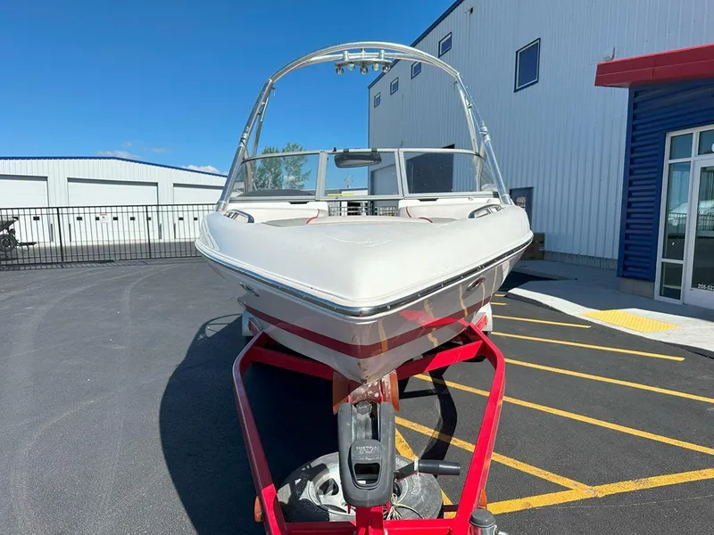 Slide: The Image of 2006 Tigé 22i boat on a red trailer, parked outside a building under a clear blue sky. - 4