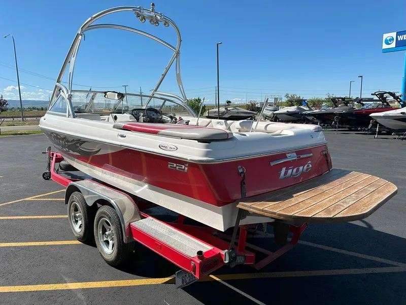 Slide: The Image of 2006 Tigé 22i boat on trailer, red and white, parked outdoors under clear sky. - 7