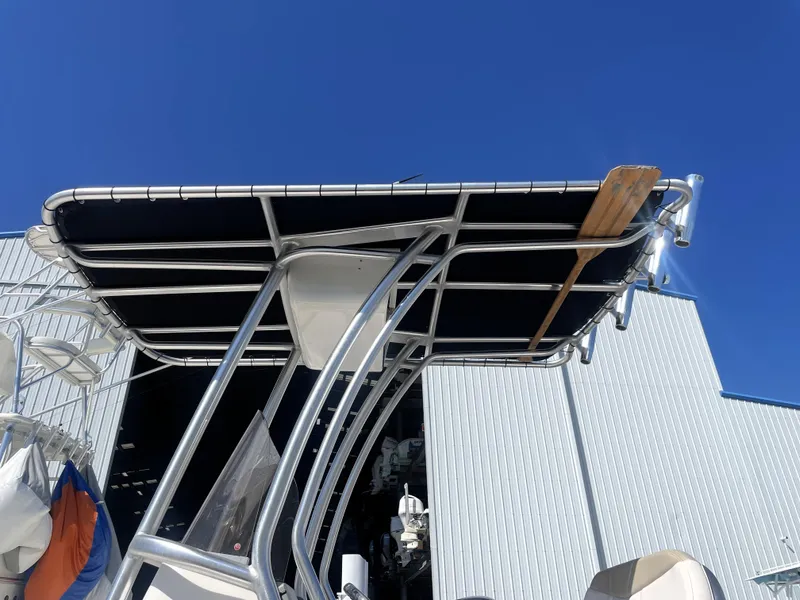 Slide: The Image of 2018 Robalo 206 Cayman boat with T-top, docked near a warehouse. - 16