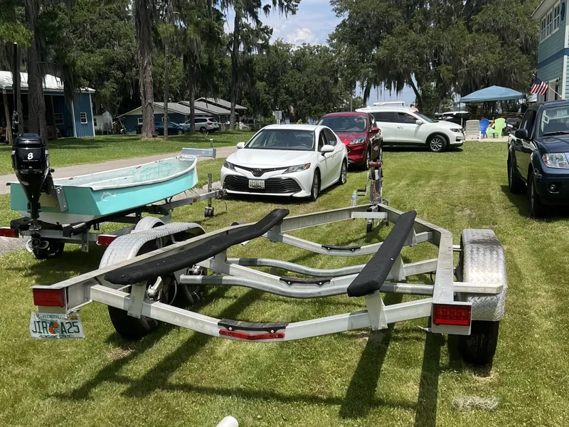 Slide: The Image of 2018 Robalo 206 Cayman boat trailer parked on grass with cars in the background. - 5