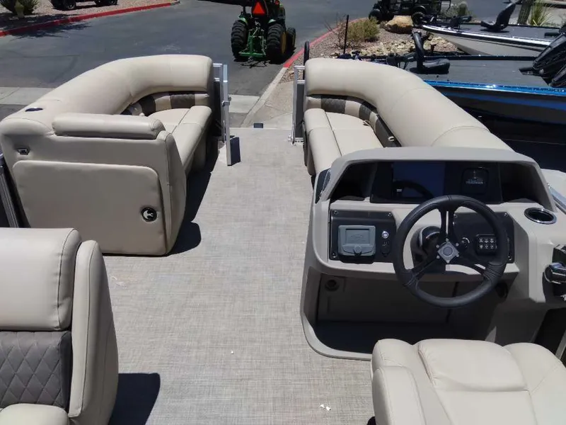 Slide: The Image of 2024 Sun Tracker Party Barge 20 DLX interior with beige seating and steering console. - 2