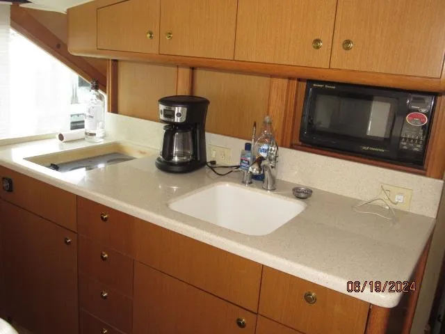 Slide: The Image of 2004 Ocean Yachts Super Sport kitchen with sink, microwave, and coffee maker. - 25