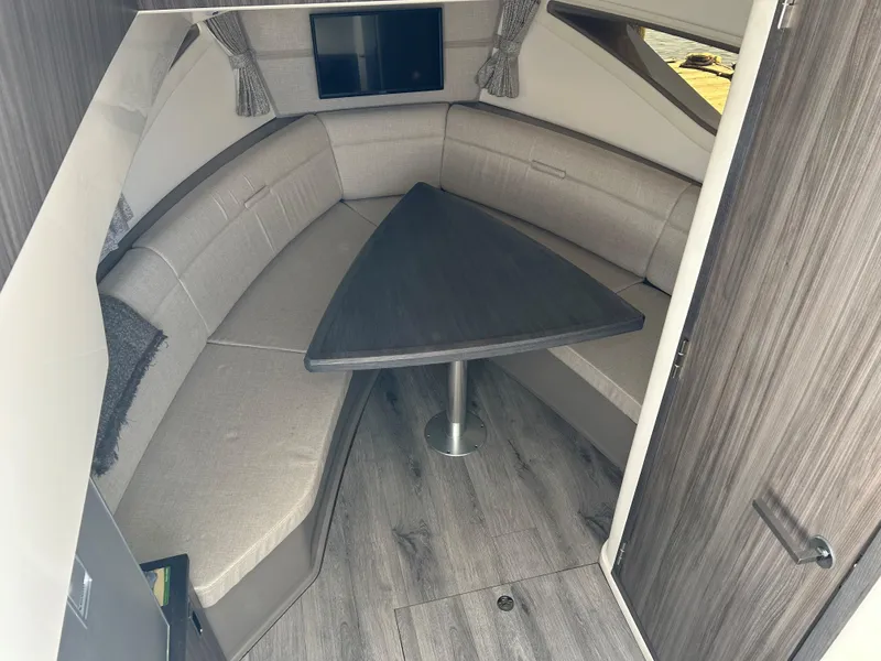 Slide: The Image of Interior of 2021 Sea Ray 320 DA boat with cushioned seating and triangular table. - 27