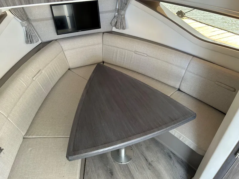 Slide: The Image of Sea Ray 320 DA 2021 interior with triangular table and cushioned seating. - 30