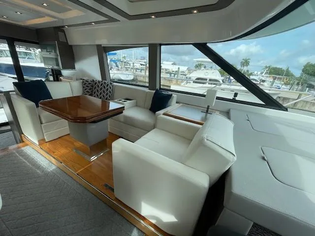 Slide: The Image of 2019 Tiara Yachts C53 Coupe interior with luxurious seating and marina view. - 14
