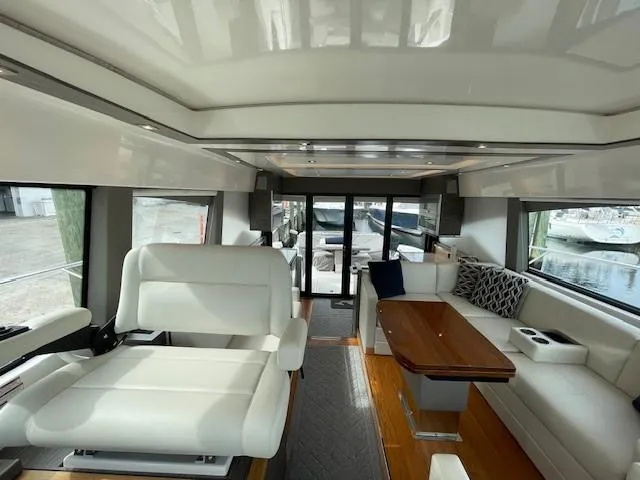 Slide: The Image of Interior of 2019 Tiara Yachts C53 Coupe with white seating and wooden table. - 19