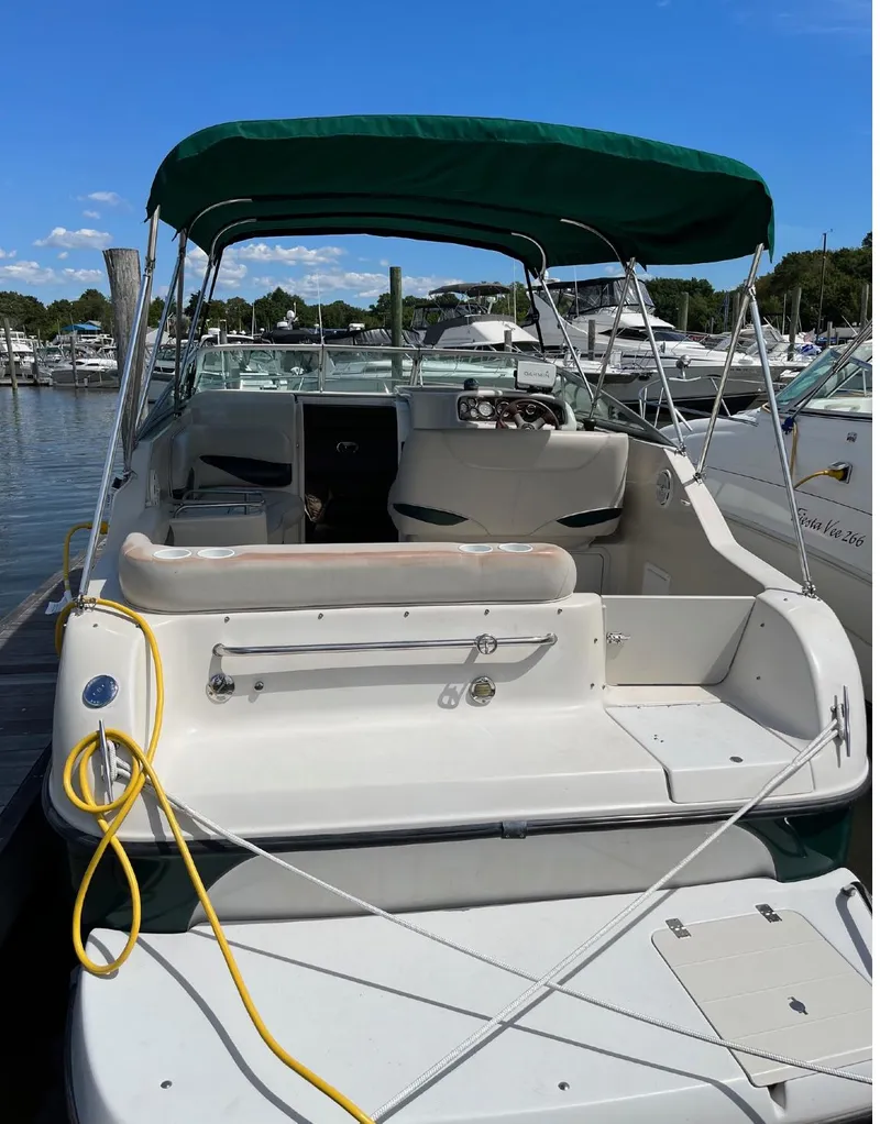 Slide: The Image of 2002 Crownline 242 CR boat docked at a marina with green canopy. - 10