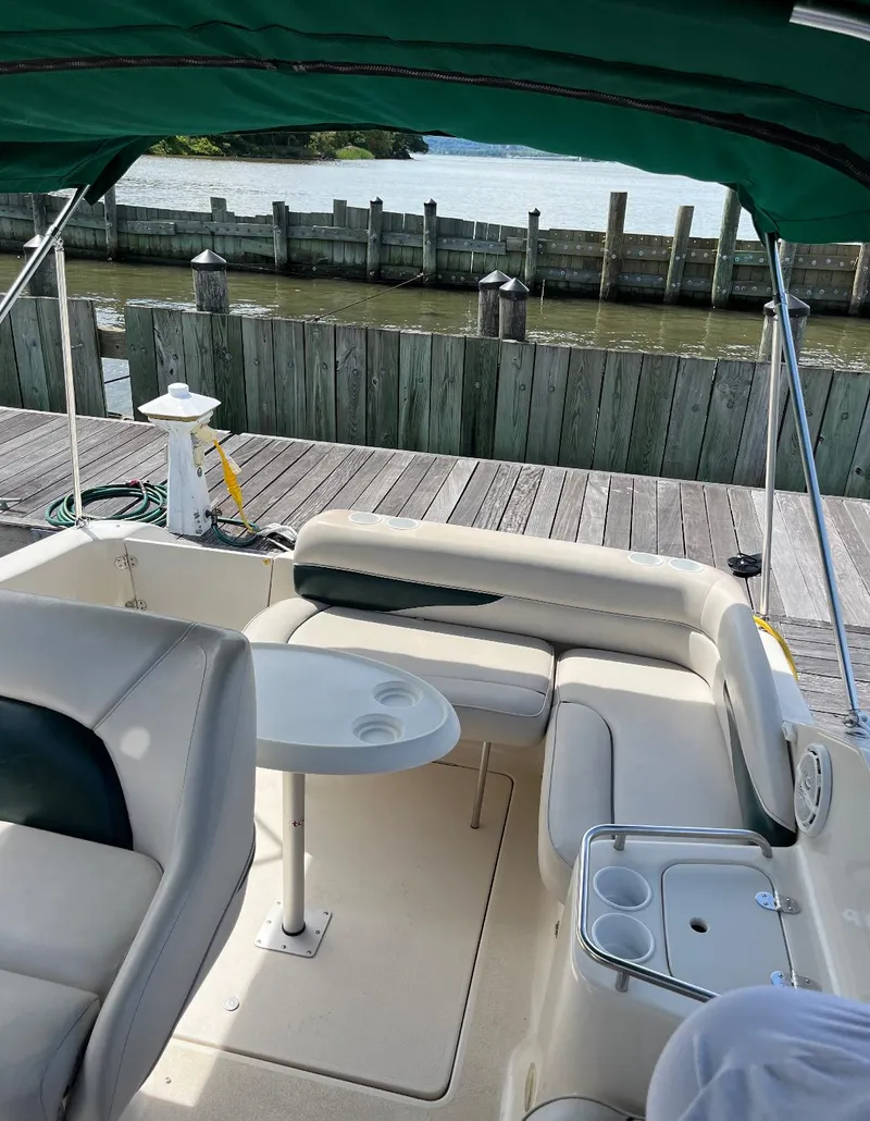 Slide: The Image of 2002 Crownline 242 CR boat interior with seating and table at dock. - 3