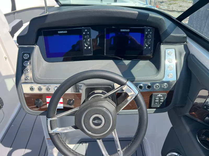 Slide: The Image of 2024 Chaparral 270 OSX boat dashboard with dual Simrad displays and steering wheel. - 9