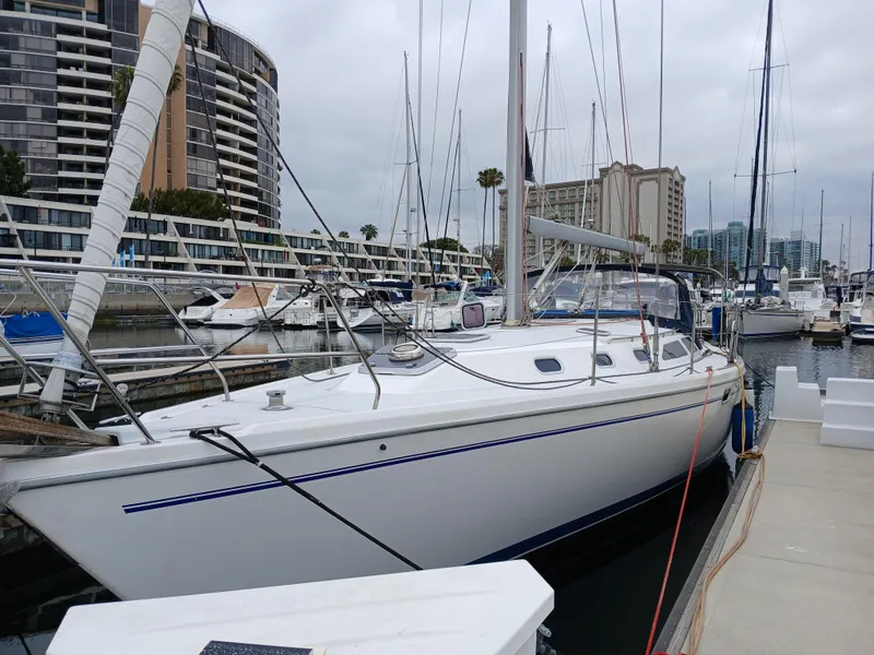 The Image of 2002 Catalina 42 MK 2 sailboat docked in a marina with modern buildings in the background. - 0