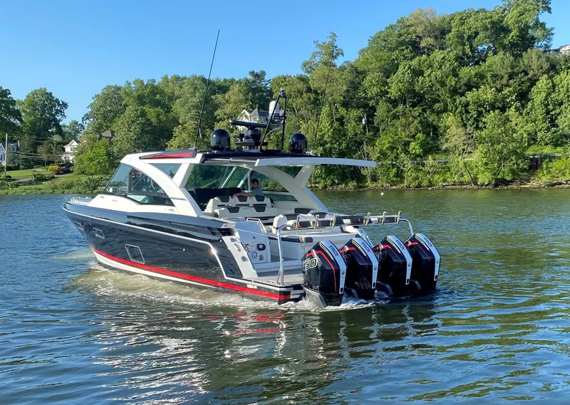 Slide: The Image of 2021 Formula 430 Super Sport Crossover boat cruising on a lake with lush green trees. - 5